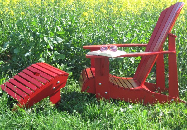 roter adirondack chair vor einem rapsfeld